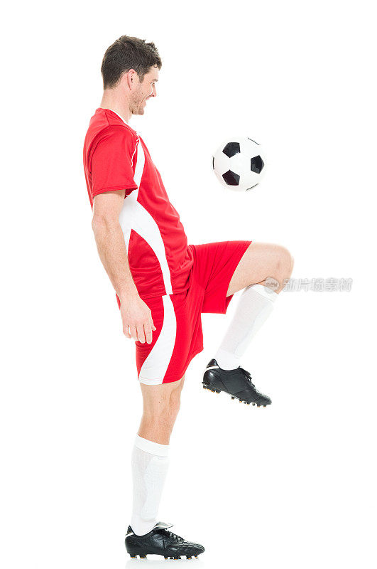 全身/一人/侧视图/ 30-39岁英俊的人的侧面视图白人男性/中年成年男子/中年成人足球运动员杂耍/穿着足球制服站在白色背景前拿着足球/球